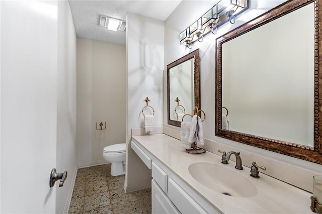 bathroom with vanity, toilet, and a textured ceiling