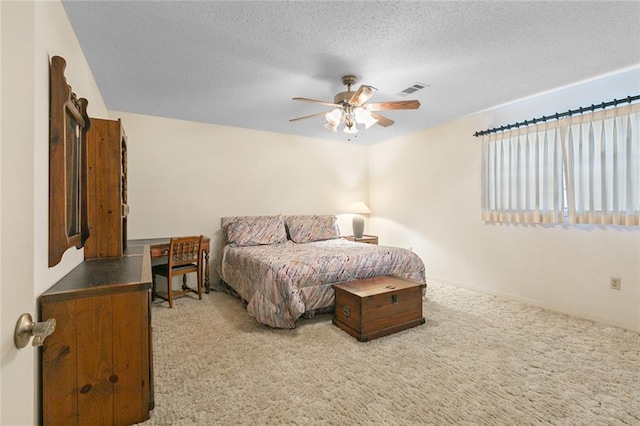 bedroom featuring ceiling fan, light colored carpet, and a textured ceiling