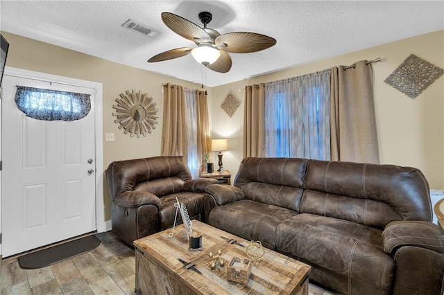 living room with ceiling fan, wood-type flooring, and a textured ceiling