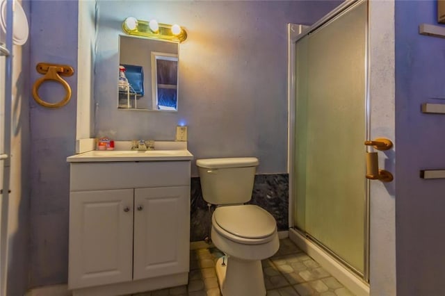 bathroom featuring vanity, toilet, and a shower with door