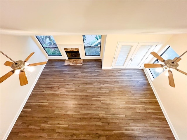 unfurnished living room with a brick fireplace, wood-type flooring, and ceiling fan