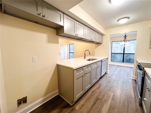 kitchen featuring sink, appliances with stainless steel finishes, a notable chandelier, gray cabinetry, and dark hardwood / wood-style flooring