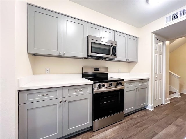 kitchen with gray cabinets, appliances with stainless steel finishes, and dark wood-type flooring