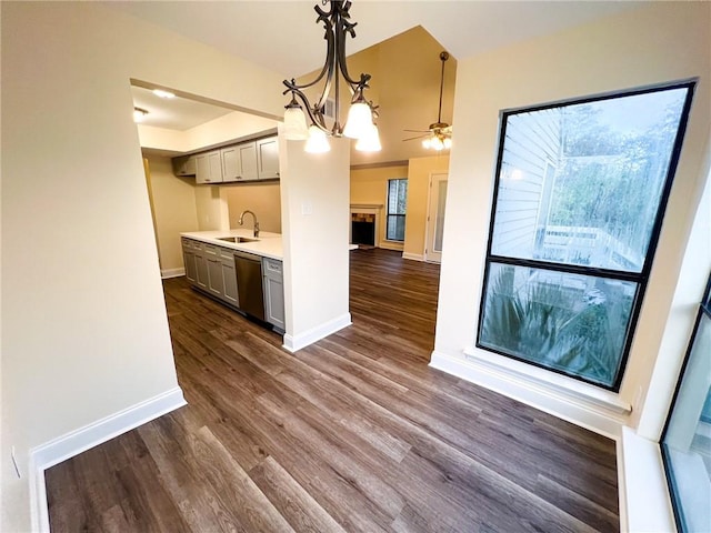 kitchen with sink, stainless steel dishwasher, hanging light fixtures, dark wood-type flooring, and gray cabinets