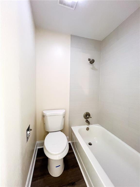 bathroom featuring hardwood / wood-style floors, tiled shower / bath, and toilet