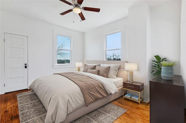 bedroom featuring hardwood / wood-style flooring, ceiling fan, and multiple windows