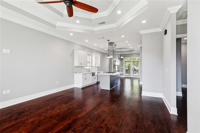 unfurnished living room with ornamental molding, french doors, dark hardwood / wood-style flooring, and a raised ceiling