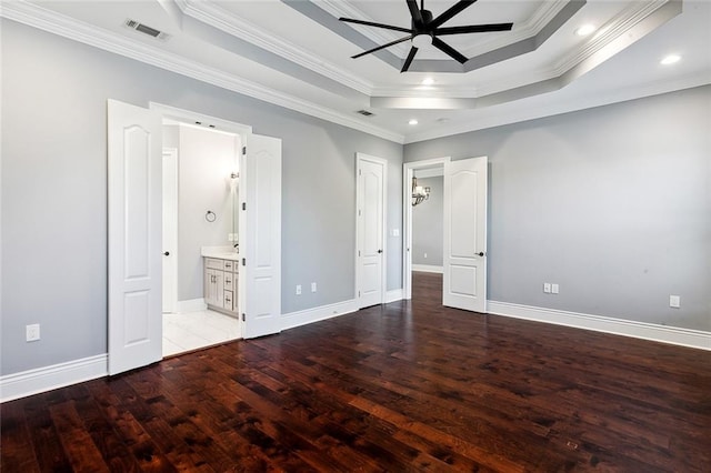 unfurnished bedroom featuring light hardwood / wood-style floors, ensuite bath, a tray ceiling, and ornamental molding