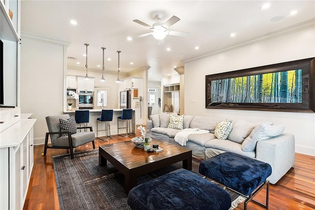 living room featuring hardwood / wood-style floors, ceiling fan, and crown molding