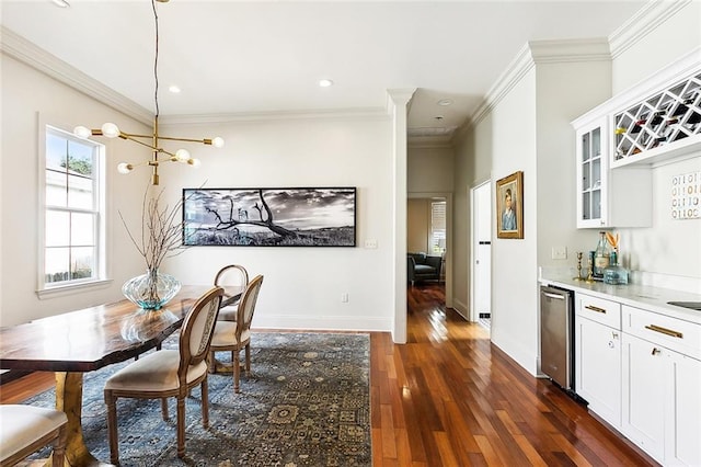 dining room featuring ornamental molding, bar, dark wood-type flooring, and a notable chandelier