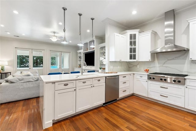 kitchen with stainless steel appliances, wall chimney exhaust hood, dark hardwood / wood-style floors, and hanging light fixtures