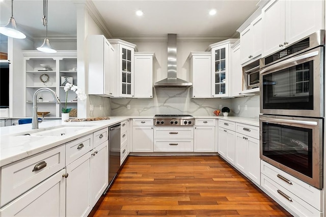 kitchen with hardwood / wood-style floors, wall chimney exhaust hood, appliances with stainless steel finishes, and ornamental molding