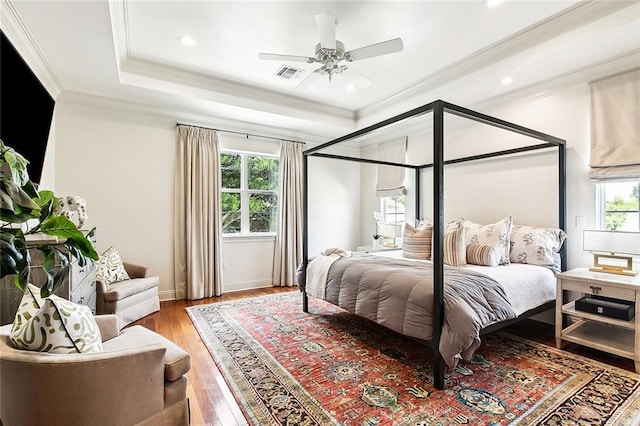 bedroom featuring ornamental molding, multiple windows, wood-type flooring, and ceiling fan