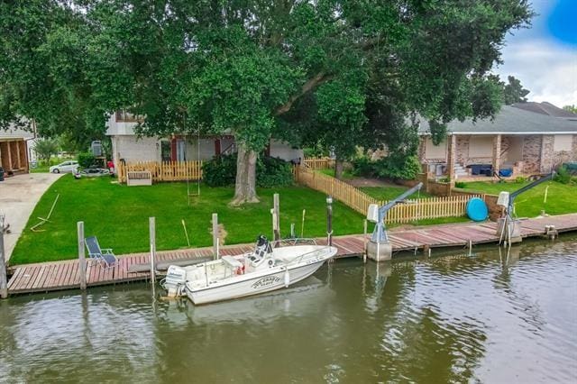 view of dock with a lawn and a water view