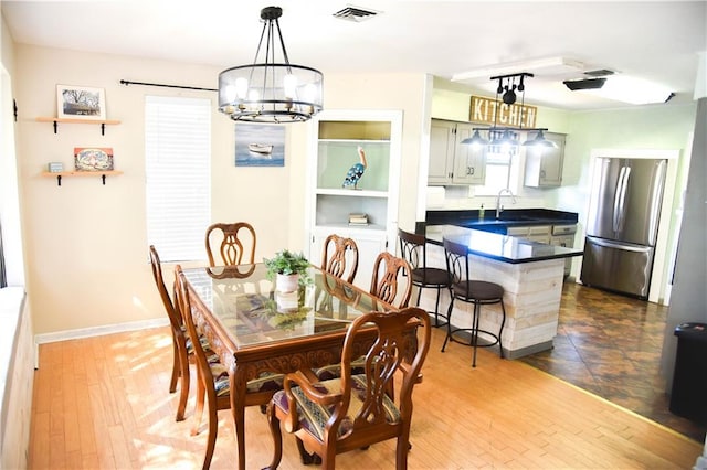 dining room with wood-type flooring, sink, and a chandelier