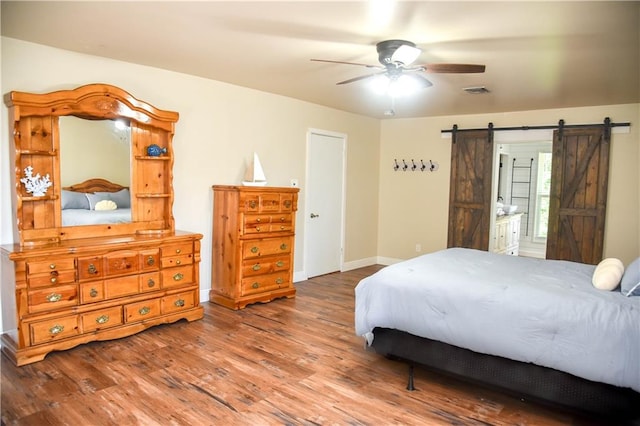 bedroom featuring wood-type flooring, a barn door, and ceiling fan