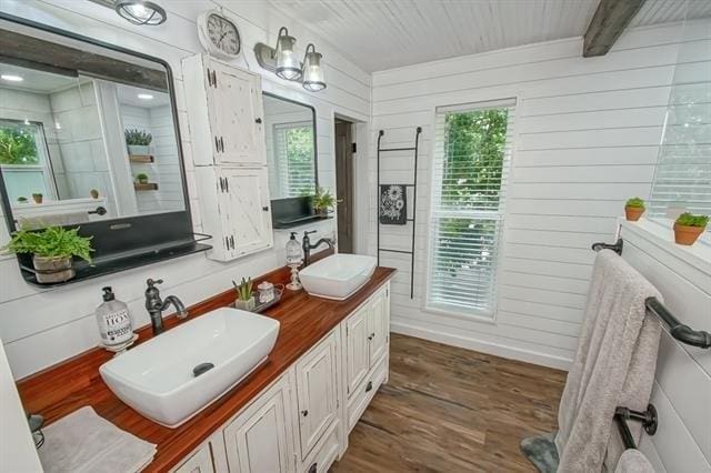 bathroom featuring wood walls, wood-type flooring, beam ceiling, and vanity