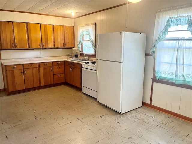 kitchen featuring wood walls, white appliances, and sink