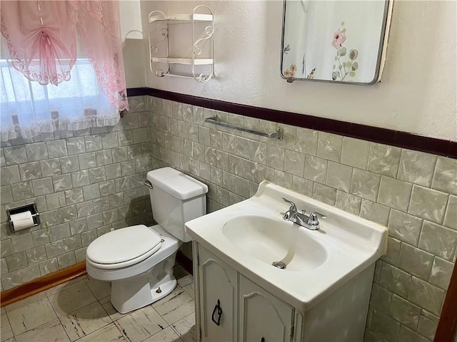 bathroom featuring toilet, vanity, and tile walls