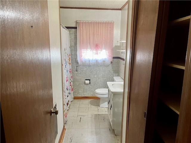 bathroom featuring toilet, vanity, and tile walls