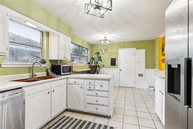 kitchen featuring kitchen peninsula, sink, a chandelier, white cabinetry, and appliances with stainless steel finishes