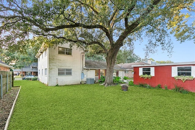 rear view of property featuring a lawn and cooling unit