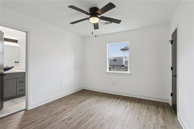 unfurnished bedroom with connected bathroom, light hardwood / wood-style floors, and ceiling fan