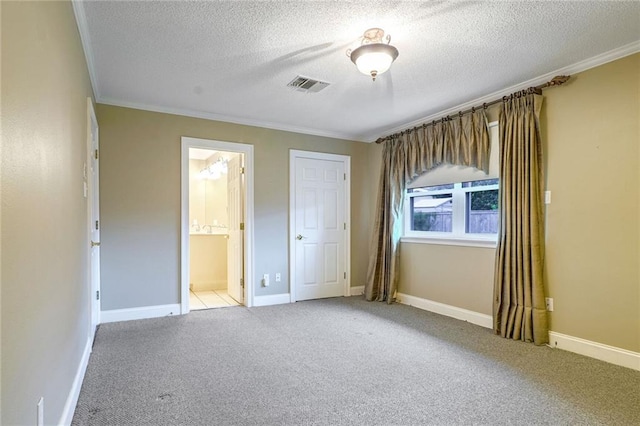 unfurnished bedroom with ornamental molding, a textured ceiling, carpet floors, and ensuite bath