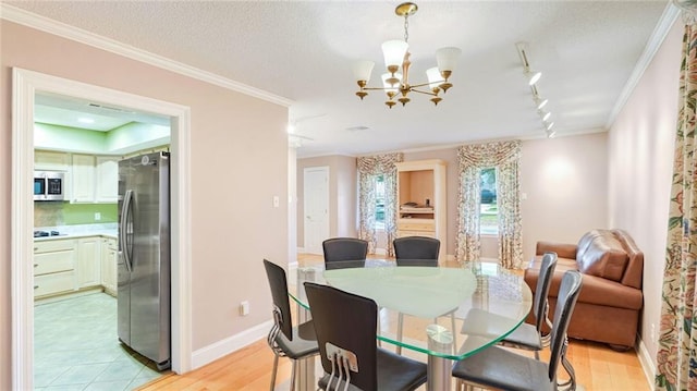 dining area with track lighting, light hardwood / wood-style floors, and crown molding