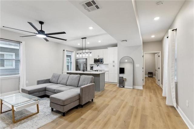 living room featuring light hardwood / wood-style floors, ceiling fan, and sink