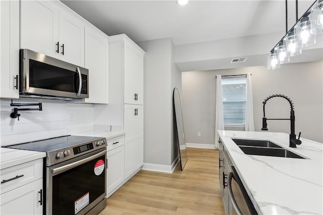 kitchen featuring light stone counters, appliances with stainless steel finishes, sink, light hardwood / wood-style floors, and white cabinets