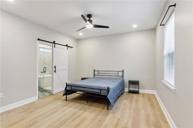 bedroom featuring multiple windows, ensuite bath, a barn door, and ceiling fan