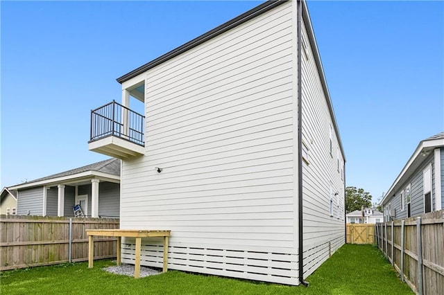 rear view of house featuring a lawn and a balcony