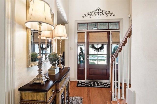 foyer entrance with hardwood / wood-style flooring, crown molding, and an inviting chandelier