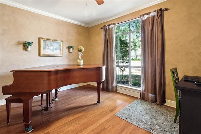 interior space featuring baseboards, ceiling fan, light wood-style flooring, and crown molding