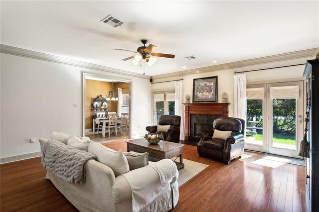 living room featuring dark hardwood / wood-style flooring, ceiling fan, ornamental molding, and a premium fireplace