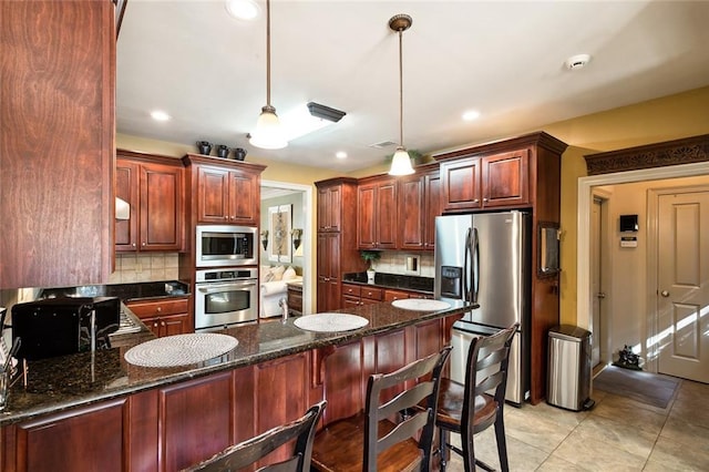 kitchen featuring dark stone counters, pendant lighting, decorative backsplash, light tile patterned floors, and appliances with stainless steel finishes