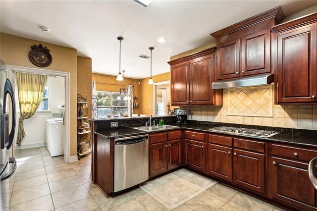 kitchen featuring sink, hanging light fixtures, dark stone countertops, decorative backsplash, and appliances with stainless steel finishes