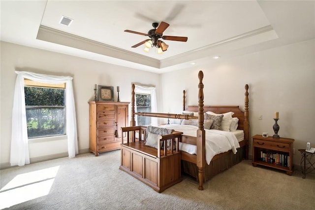 bedroom with ornamental molding, a raised ceiling, light colored carpet, and visible vents