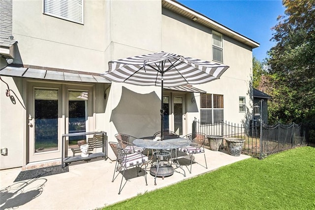 back of property featuring fence, a yard, a patio, and stucco siding