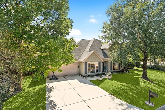 view of front facade with an attached garage, a shingled roof, driveway, stucco siding, and a front yard