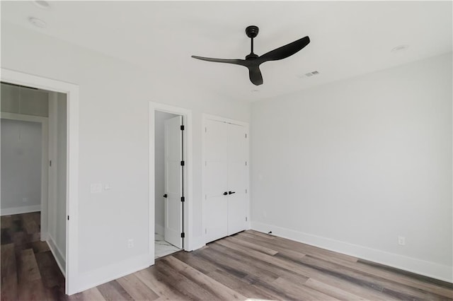 unfurnished bedroom with ceiling fan, ensuite bath, and hardwood / wood-style floors