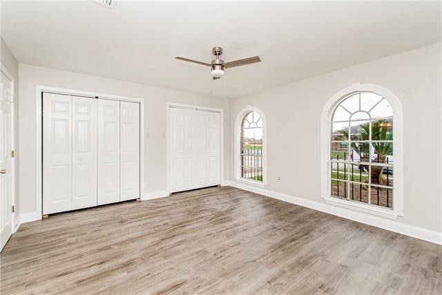 unfurnished bedroom with light hardwood / wood-style flooring, ceiling fan, and two closets