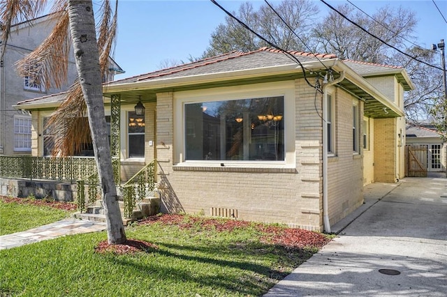 bungalow-style house with a front yard, crawl space, brick siding, and fence