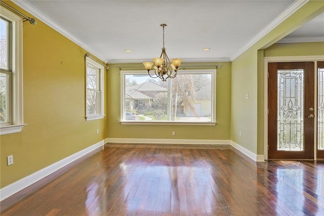 unfurnished dining area with crown molding, a notable chandelier, hardwood / wood-style flooring, and baseboards