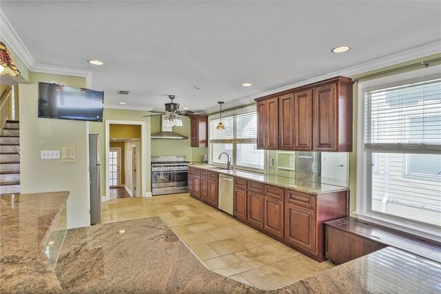 kitchen featuring appliances with stainless steel finishes, crown molding, wall chimney range hood, and a sink