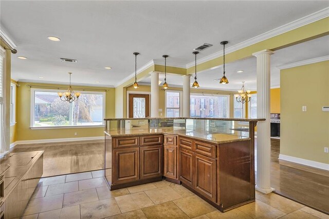 kitchen featuring visible vents, ornamental molding, brown cabinets, light stone countertops, and an inviting chandelier