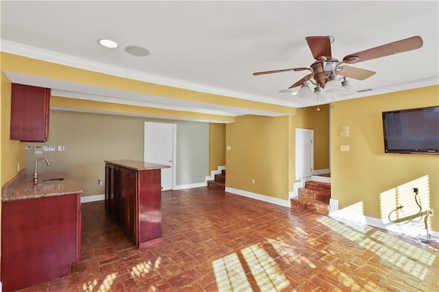 kitchen with ornamental molding, a center island, sink, and ceiling fan