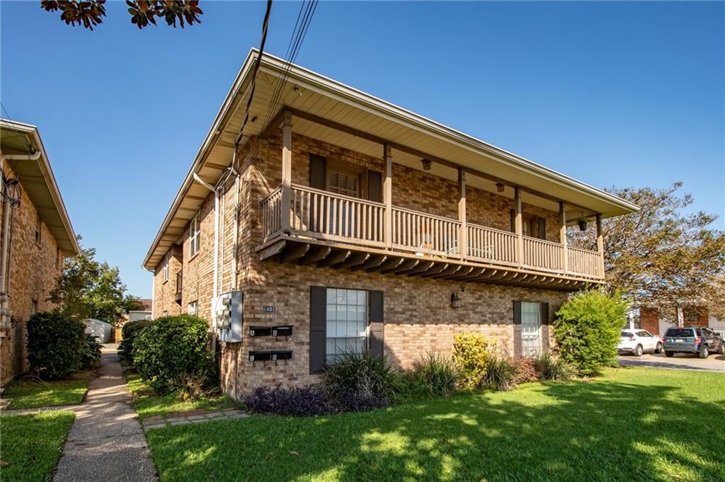 exterior space featuring a front lawn and a balcony