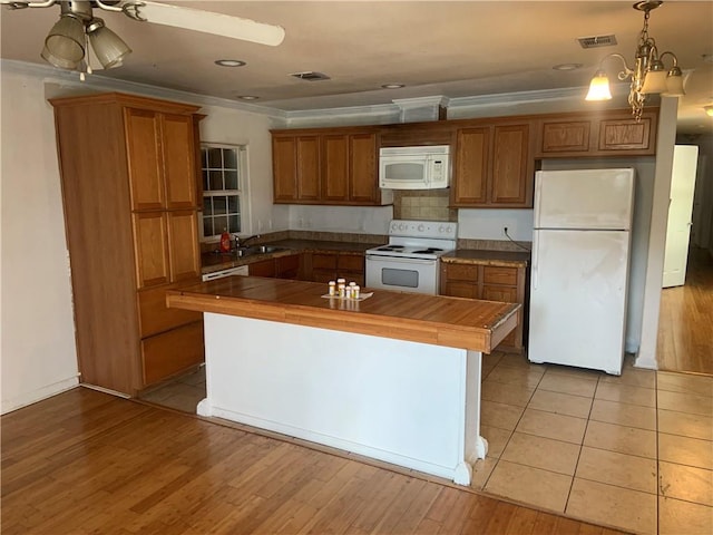 kitchen with ornamental molding, ceiling fan with notable chandelier, white appliances, decorative light fixtures, and light hardwood / wood-style floors